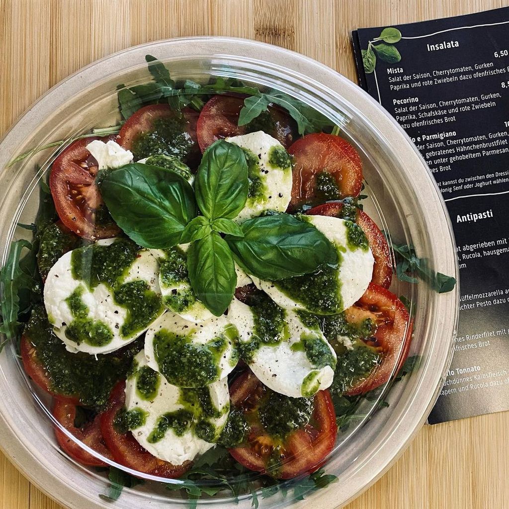 Auf diesem Photo ist Caprese zu sehen. Er enthält Rucola, Tomaten, Mozarella und Pesto oben drauf
