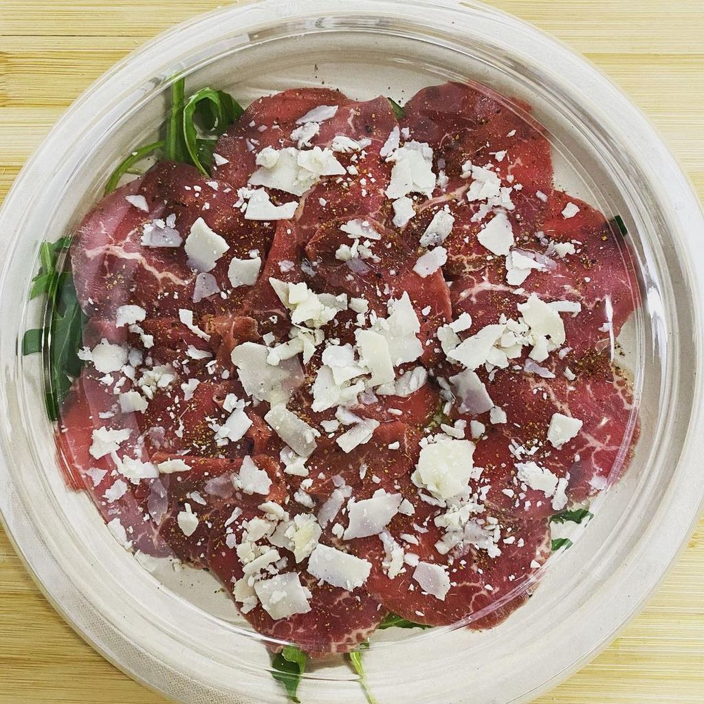 Hier ist Carpaccio zu sehen. Es besteht aus hauchdünnem Rinderfilet, was mit gehobelten Parmesan überstreut wird